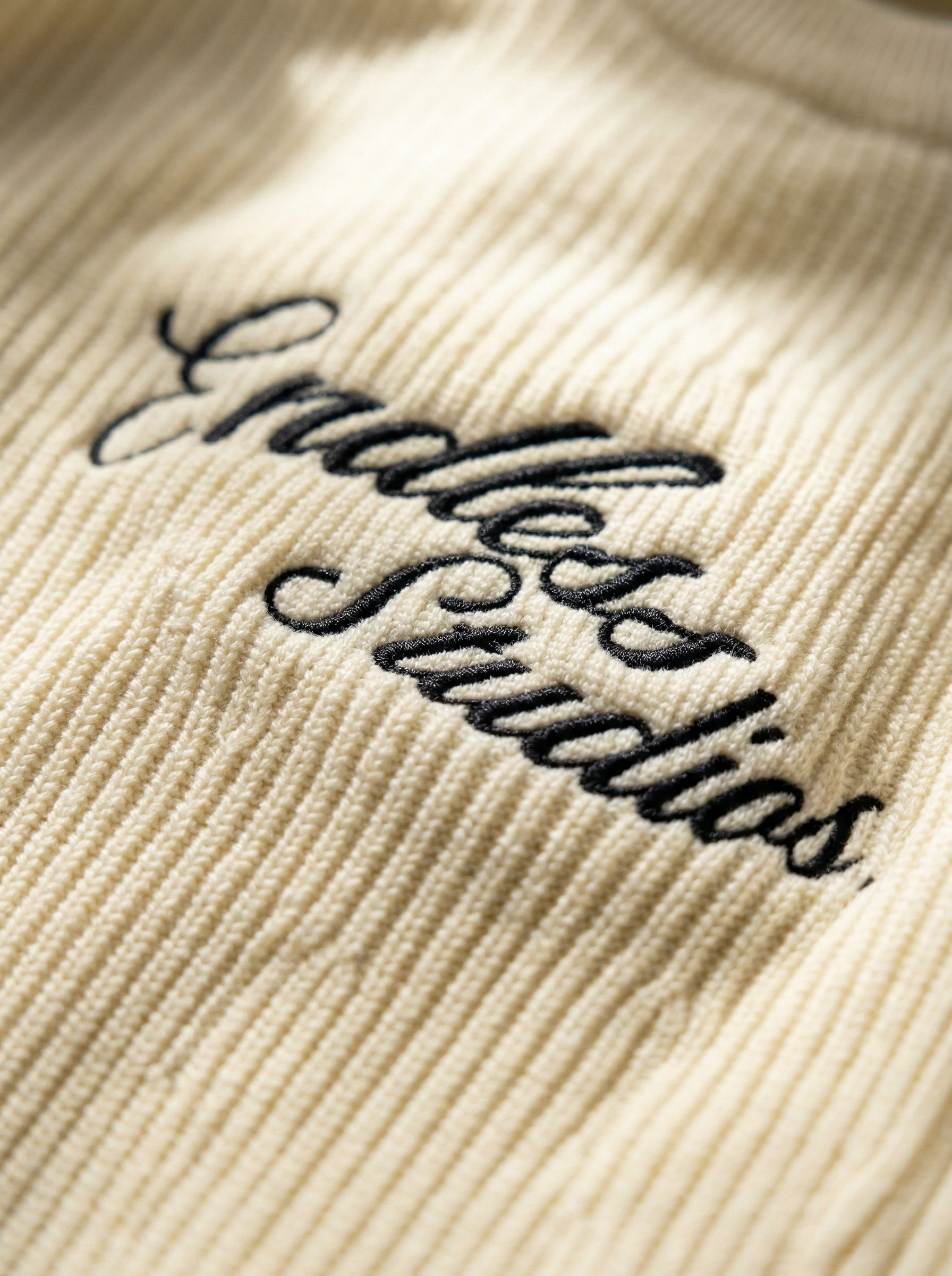 Endless Studios script embroidery macro — cream corduroy fabric